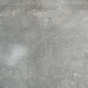 A close-up view of a smooth, gray concrete surface with some subtle texture and light patches.