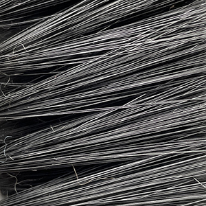 Close-up view of a large bundle of thin, metallic wires stacked closely together, creating a dense, textured pattern with varying shades of gray and silver.