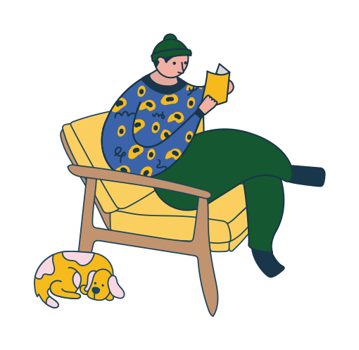 A person wearing a green beanie and a blue patterned sweater sits on a yellow chair reading a book, while a small dog with yellow and white fur sleeps curled up on the floor beside them.