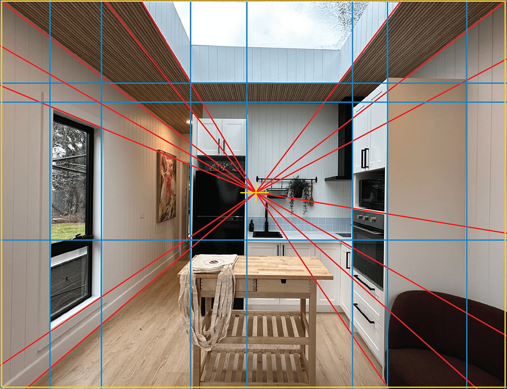 A modern kitchen with white walls, wood floors, and a central wooden island. Red and blue lines form a grid, showing perspective and alignment, with a skylight above and large windows on the left.